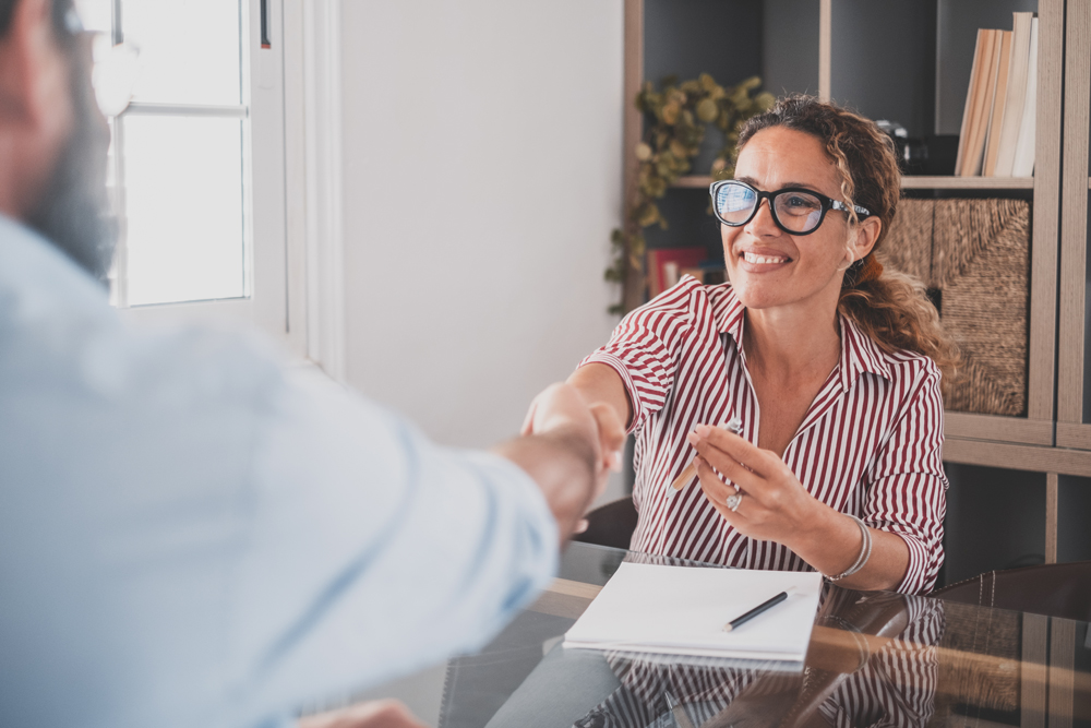 woman in glasses hires man and shakes his hand